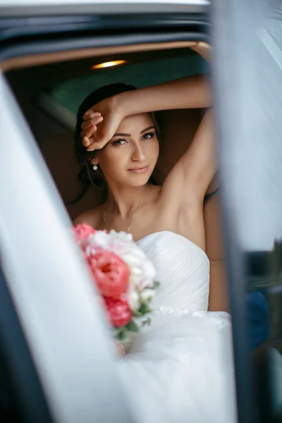 Atractiva novia caucásica sentada en el coche y sonreír a la cámara — Foto de Stock