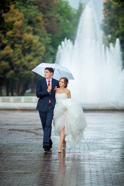 幸せの結婚式で新郎新婦の歩く白い傘 — ストック写真