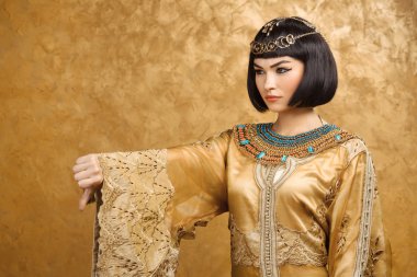 Kleopatra gibi altın arka planda başparmak aşağı jest ile ciddi Mısırlı kadın