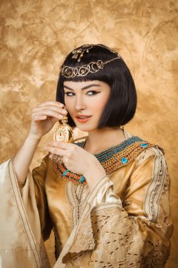 Altın arka planda parfüm şişesi ile Kleopatra gibi Güzel Mısırlı kadın