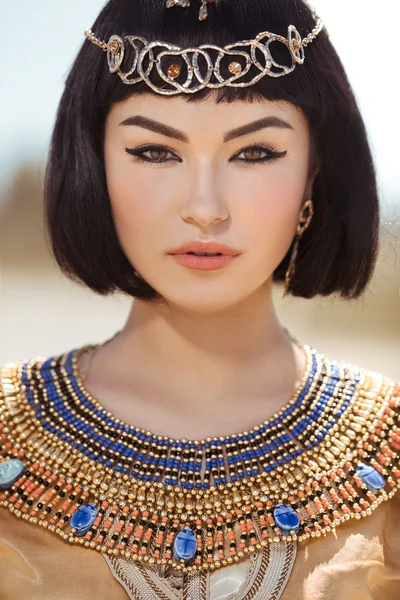 Όμορφη γυναίκα με μόδας μακιγιάζ και χτένισμα σαν αιγυπτιακή βασίλισσα Κλεοπάτρα σε εξωτερικούς χώρους κατά της ερήμου — Φωτογραφία Αρχείου