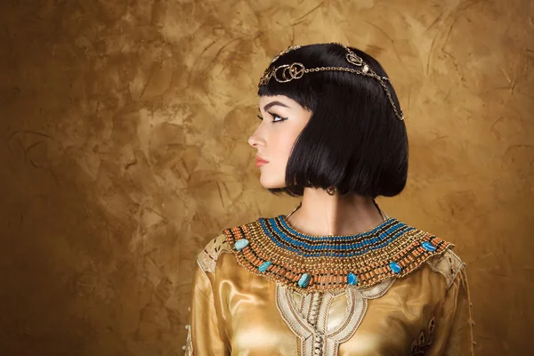 Beautiful woman like Egyptian Queen Cleopatra on golden background. Side view, face profile Stock Picture