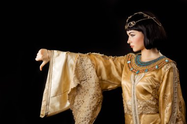 Siyah arka plan üzerinde başparmak aşağı jest ile Kleopatra gibi Ciddi Mısırlı kadın