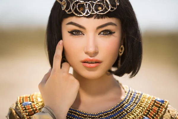 Mooie vrouw met mode make-up en kapsel zoals Egyptische koningin Cleopatra buitenshuis tegen woestijn — Stockfoto