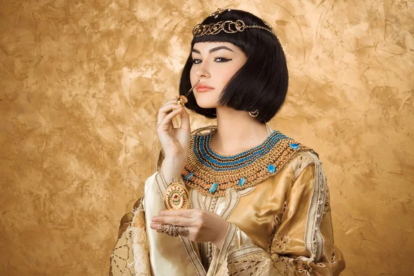 Beautiful Egyptian woman like Cleopatra with perfume bottle on golden background — Stock Image Beautiful Egyptian woman like Cleopatra with perfume bottle on golden background Stock Image