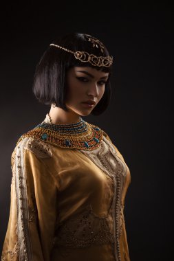 Siyah arka plan üzerinde serius yüzü ile Mısır Kraliçesi Kleopatra gibi güzel kadın.