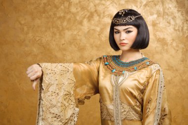 Kleopatra gibi altın arka planda başparmak aşağı jest ile ciddi Mısırlı kadın