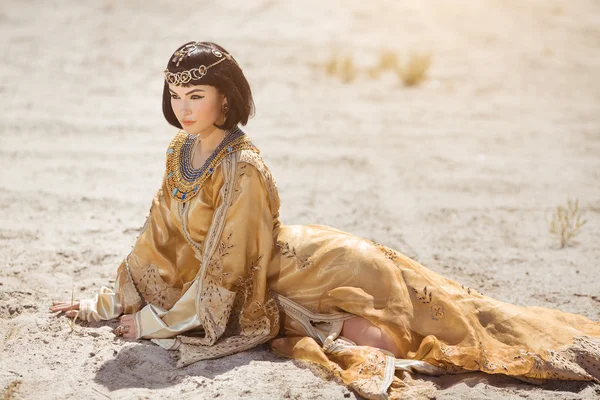 Mulher bonita como a rainha egípcia Cleópatra deitado no deserto ao ar livre . — Fotografia de Stock