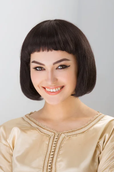 Menina sorridente com maquiagem Cleopatras e corte de cabelo posando em estúdio — Fotografia de Stock