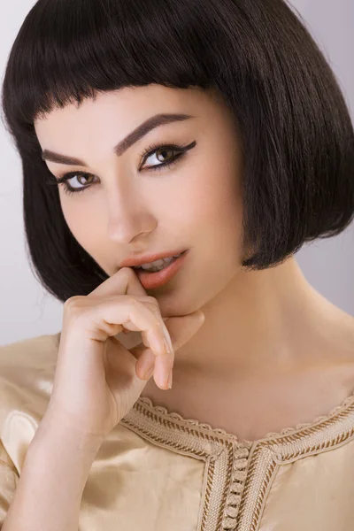 Chica sonriente con Cleopatras maquillaje y corte de pelo posando en el estudio — Foto de Stock