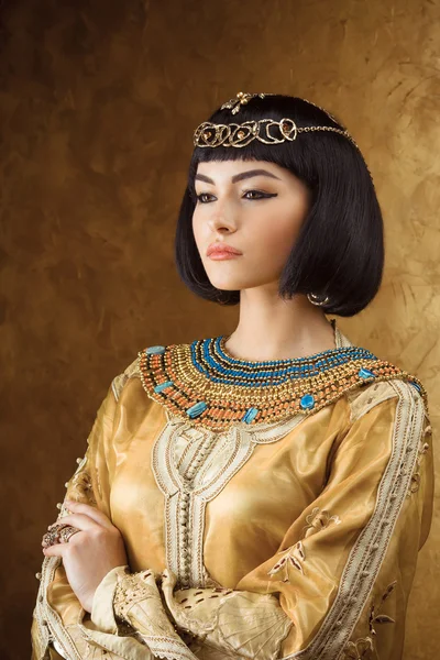 Beautiful Egyptian woman like Cleopatra on golden background — Stock Photo, Image