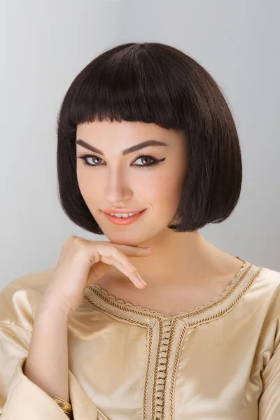 Smiling girl with Cleopatras make-up and haircut posing in studio — Stock Photo, Image