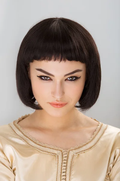 Ernsthafte andgy girl mit cleopatras make-up und haarschnitt posieren im studio — Stockfoto