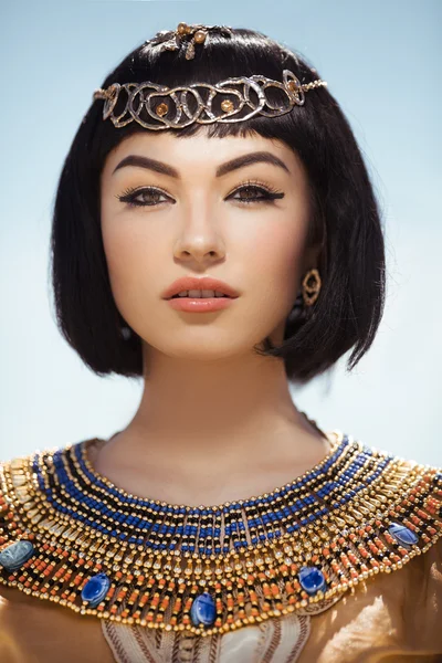 Beautiful woman with fashion make-up and hairstyle like Egyptian queen Cleopatra outdoors against desert — Stock Photo, Image