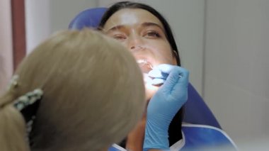 Kadın bir hastaya diş tedavisi yapan bir diş hekimi..