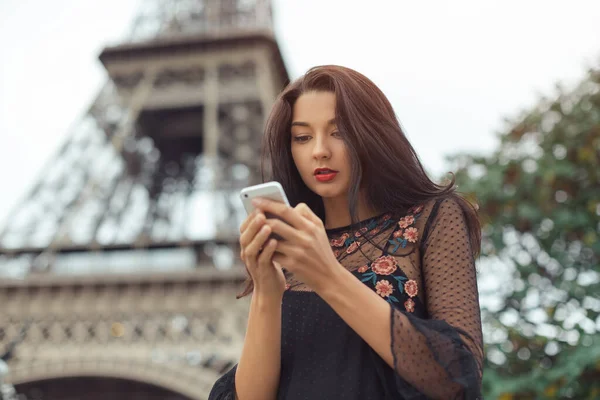 Frau mit Smartphone in der Nähe von Eiffelturm und Karussell, Paris. — Stockfoto