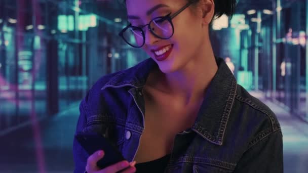 Женщина, использующая смартфон в городе ночью — стоковое видео