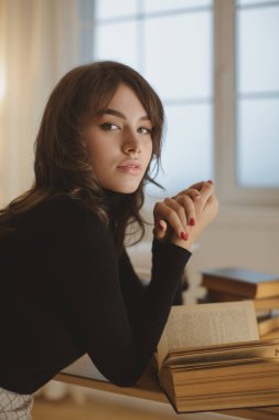 Evde kitap okuyan genç bir kadın.