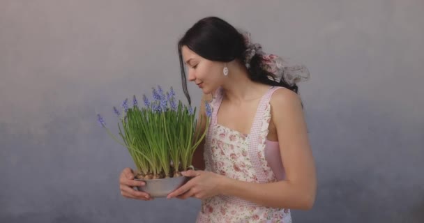 Mujer sosteniendo racimo de flores en maceta en interiores — Vídeo de stock