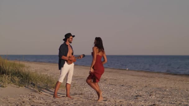 Casal apaixonado tocando guitarra e dançando na praia — Vídeo de Stock