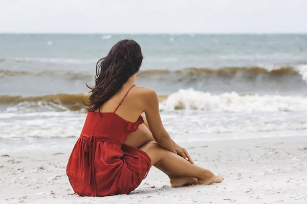 海滩上的红衣女子，寒冷的风天气 — 图库照片