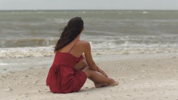 Frau in Rot am Strand, kaltes, windiges Wetter — Stockvideo