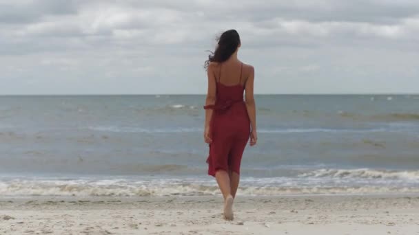 Vrouw in het rood op het strand, koud weer — Stockvideo