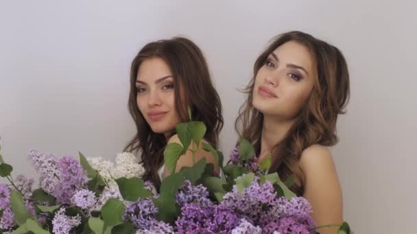 Studio fashion portrait photo of two twins women with a bouquet of spring flowers — Stockvideo