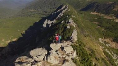 Bir dağın tepesinde sırt çantalı bir çift turistin hava görüntüsü