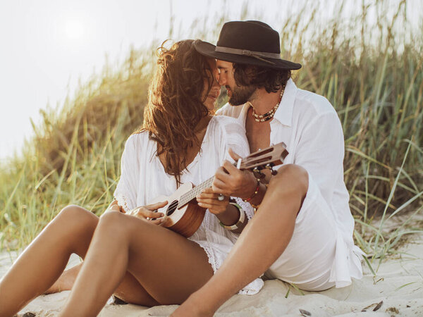 Couple in Love Playing Guitar and Resting on the Beach