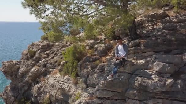 Luftaufnahme eines jungen Mannes, der auf Felswand gegen das Meer fährt. — Stockvideo
