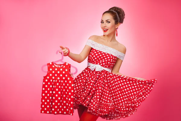 Szczęśliwa kobieta trzyma się Kidswear. Pin-Up w stylu Retro. — Zdjęcie stockowe