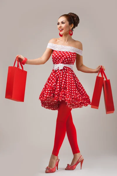Boldog asszony feltartotta bevásárló táskák. Pin-up retro stílusú. — Stock Fotó