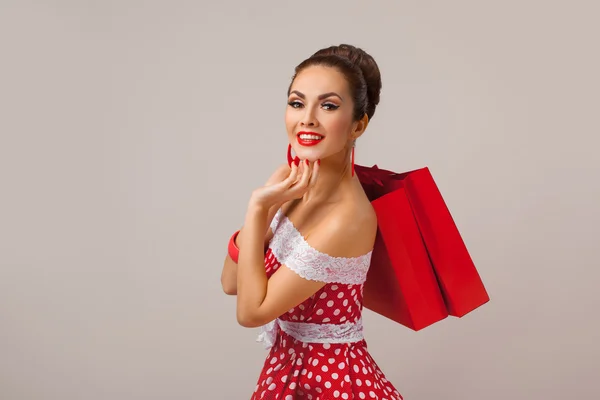 Gelukkige vrouw bedrijf boodschappentassen. Pin-up retro stijl. — Stockfoto