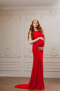Kırmızı elbiseli hamile bir modeldir