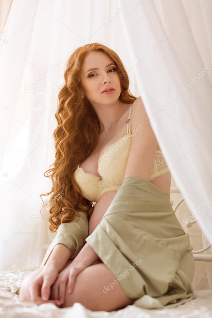 Beautiful young pregnant woman sitting in bed at home