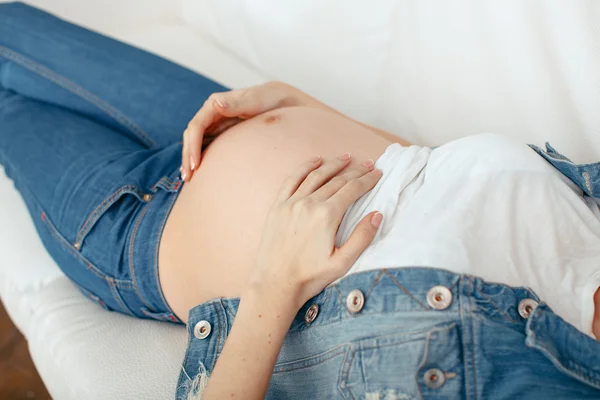 Donna incinta rilassante a casa, primo piano della pancia — Foto Stock