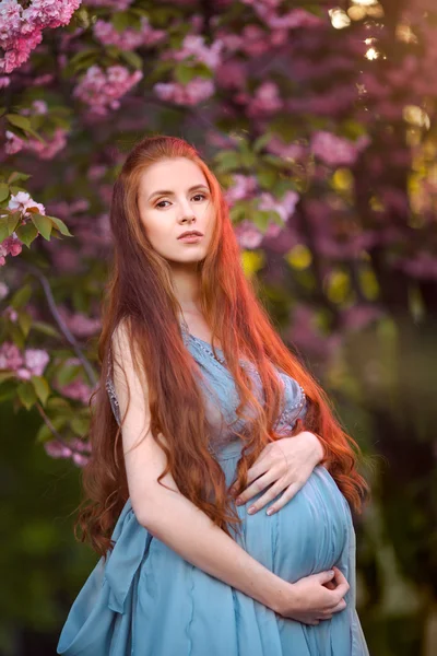 Vacker gravid kvinna i blommande trädgård — Stockfoto