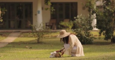 Hasır şapkalı şık bir kadının güneşli bir tatil köyü bahçesinde çimlerden hindistan cevizi toplaması. Seyahat, sağlık veya eko-yaşam tarzı video içeriği için ideal.