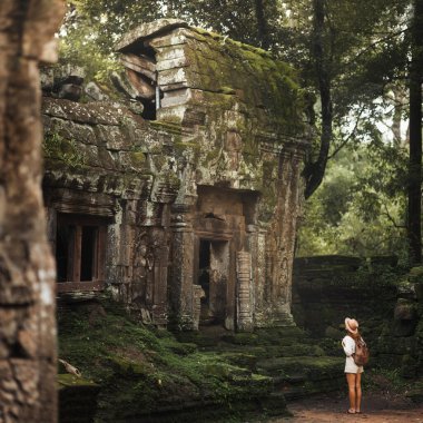 Kamboçya 'daki Ta Prohm Tapınağı' nın yosun kaplı kalıntılarını araştıran sırt çantasıyla gezgin, macera konsepti, miras turizmi, arkeoloji, tarih ve kültür..