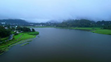Gregory Gölü 'nün Nuwara Eliya, Sri Lanka' daki hava görüntüleri yemyeşil ve sisli tepelerle çevrili. Doğa, turizm veya manzara tanıtımı için kavramsal seyahat videosu.