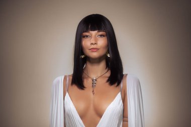 Siyah kısa saçlı, beyaz elbisesi ve takıları olan zarif bir kadın. Moda yazıları, lüks reklamlar ve yaşam tarzı kavramları için ideal..