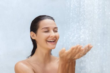Kafkasyalı mutlu kadın ferahlatıcı bir duşun altında gülümsüyor, güzel bir anın tadını çıkarıyor. Cilt bakımı, kaplıca ya da temiz ve parlak titreşimli hijyen konsepti tanıtımı için mükemmel..