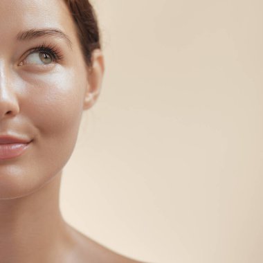 Beyaz tenli, parlak tenli, bej arkaplan sahibi, promosyon metni için yer açan beyaz bir kadının yakın plan yarım yüzü. Güzellik afişleri, kaplıca reklamları ve cilt ürünleri markalaşması için mükemmel..
