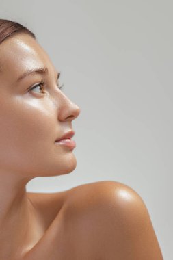 Profil görünümünde pırıl pırıl beyaz tenli beyaz bir kadın, temiz bir stüdyo ortamında yukarı bakıyor. Cilt bakımı reklamları, yüz yapısı odağı, güzellik makaleleri ve kozmetik markalaşma için mükemmel.. 