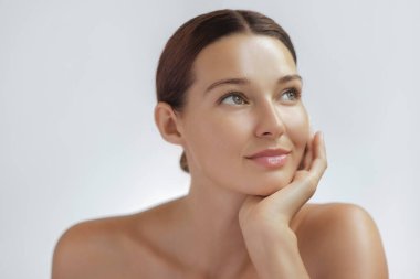 Işıl ışıl parlayan cildi ve doğal makyajı elinde dinlenen beyaz bir kadının yüksek kaliteli portresi. Cilt bakımı, kaplıca, sağlık ve güzellik anlayışı.