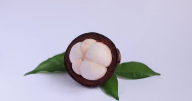 Taze bir mangosengi yarım kalmış bir meyvenin ve yeşil yaprakların yanına yerleştiren bir el. Sağlıklı beslenme, tropikal meyve promosyonları ve yemek fotoğrafçılığı için mükemmel.. 