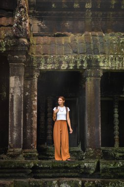 Kamboçya 'daki Angkor Wat kalıntılarını araştıran sırt çantalı turist kadın, Khmer kültür ve tarihinin sembolü, yaşam tarzı, kültürel seyahat, miras turizmi, maneviyat ve macera konsepti.