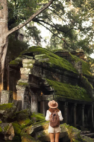 Kamboçya 'daki Ta Prohm Tapınağı' nda yosun kaplı kalıntıları araştıran sırt çantalı kadın gezgin, macera konsepti, yaşam tarzı, tarih, arkeoloji, turizm ve