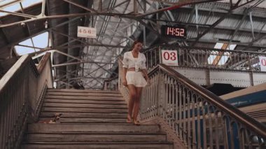 Beyaz elbiseli şık bir kadın Sri Lanka 'daki Colombo Fort tren istasyonunda merdivenlerden iniyor. Bu seyahat görüntüleri, turizm ve turizm için mükemmel olan tarihi mimari ve canlı atmosferi yakalar.